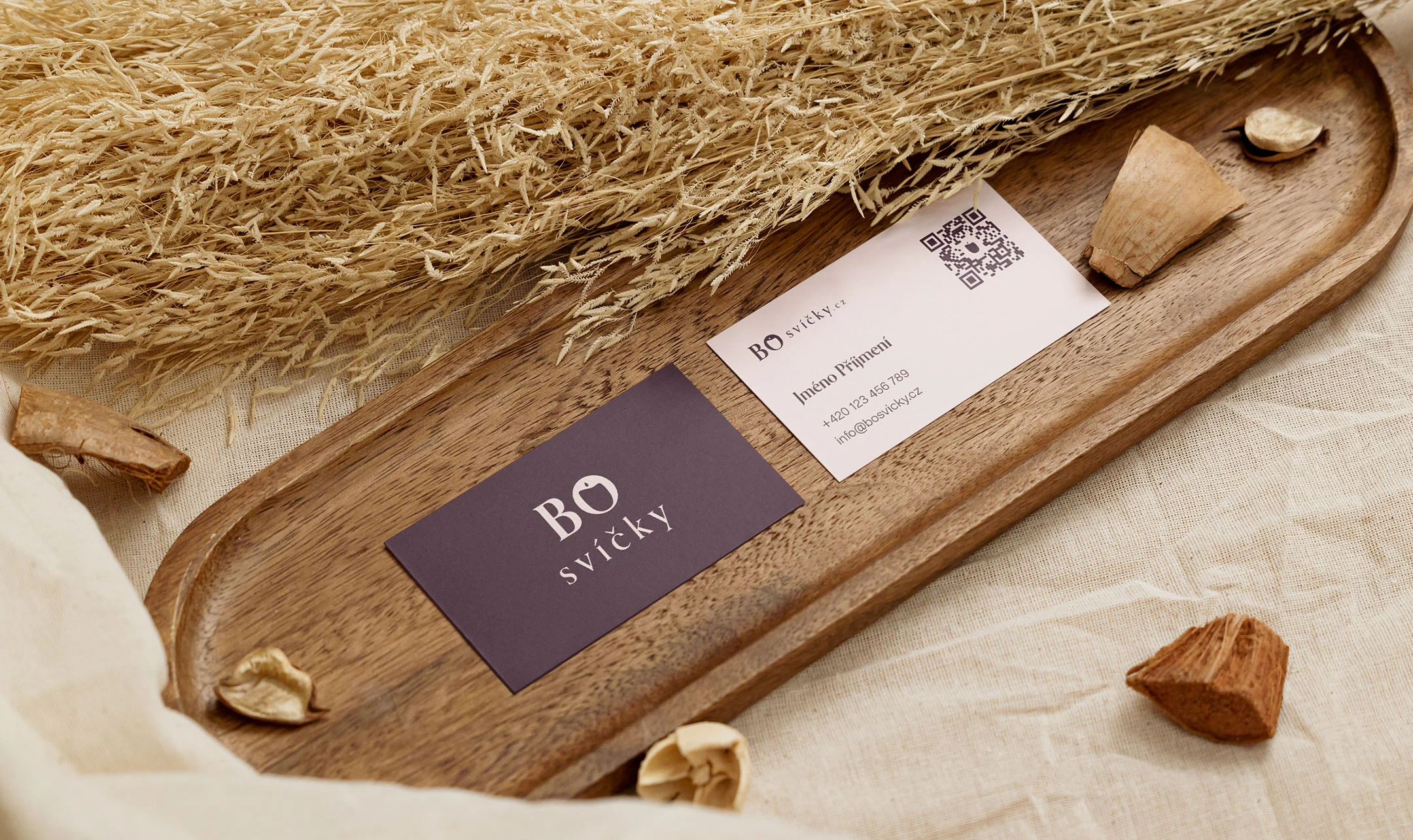 Front and back of the BO svíčky business cards on a wooden tray