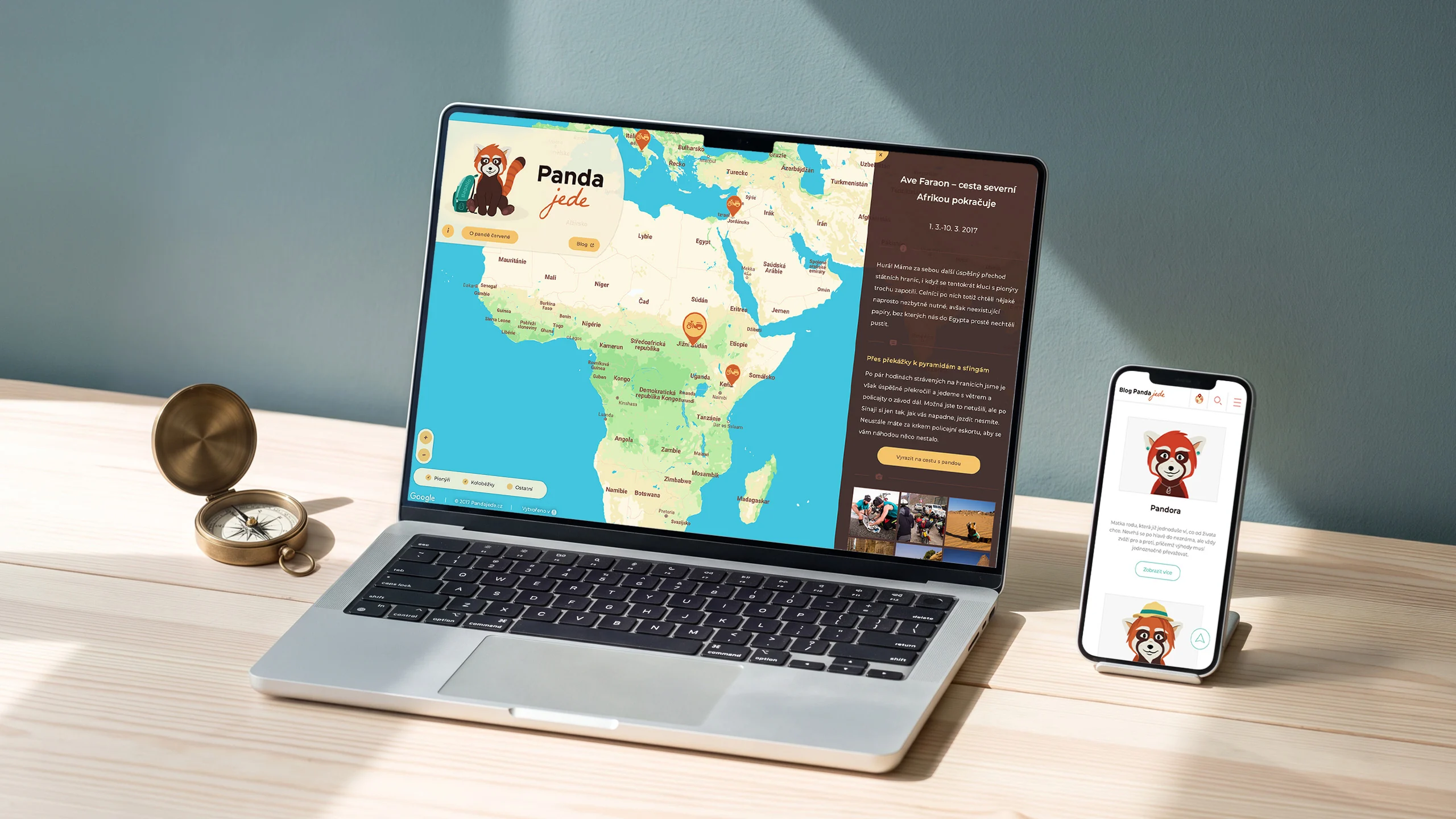 Laptop with an Africa route map and a phone with the Panda jede blog on a wooden desk by a teal wall